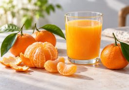 Vaso de zumo de mandarina junto a mandarinas enteras, una pelada y varios gajos